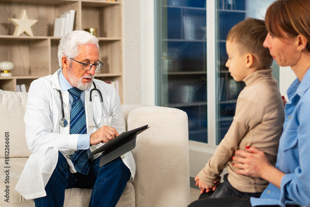 Obraz premium Visit to pediatrician doctor. Mother with little preschooler son visit consult male pediatrician at hospital. Doctor examining boy. Family and doctor have consultation in doctor office clinic at home
