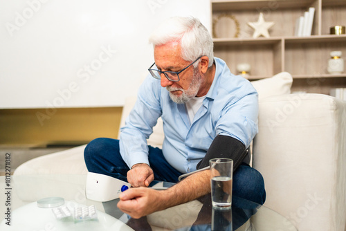 Hypertension problem in senior age. Old man measuring blood pressure with tonometer at home. Senior man have health problem making self checkup. Headache treatment of hypertension hypotension