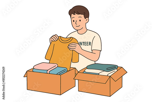 Volunteer packing donated clothing items into open cardboard boxes for charity work