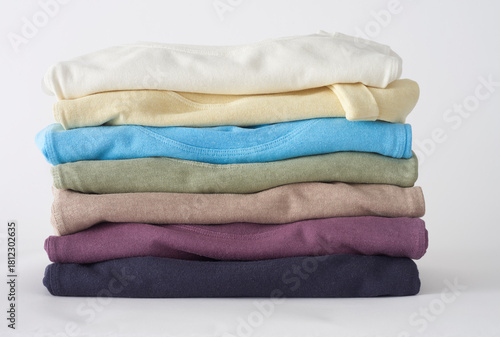 Stack of folded colorful baby clothes newborn apparel on white background