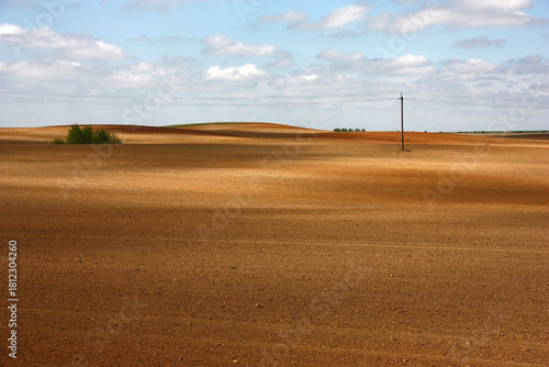 Sunny spring day. In the sky white clouds. The extensive processed fields in spots of light and shade.