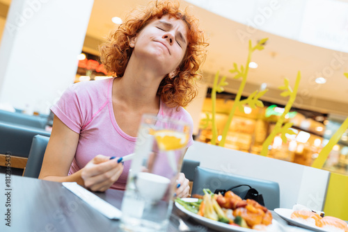 attractive redhead teen girl eating chinese soup in fast food restaurant
