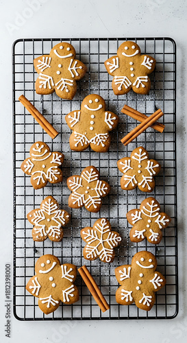 Overhead shot of gingerbread cookies and cinnamon sticks on black metal cooling rack