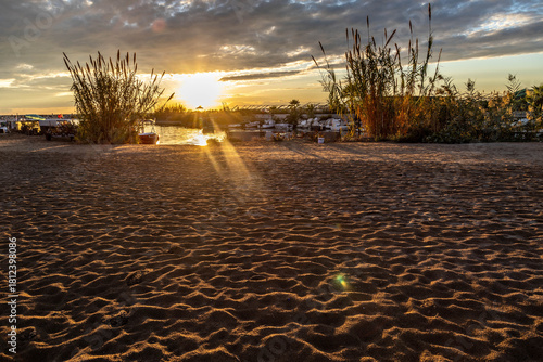 Fototapeta Naklejka Na Ścianę i Meble -  Wavy sand patterns on a river beach at sunset, with long shadows and silhouetted reeds in beautiful backlight. Evrenseki, Antalya, Turkey, Mediterranean.

