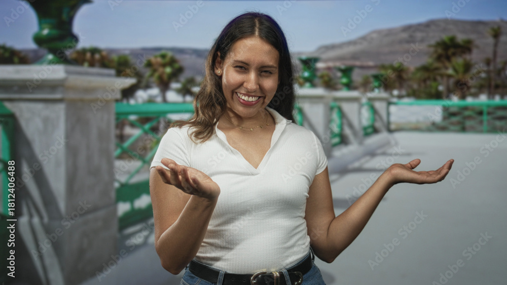Fototapeta premium Woman showing open palms in a shrug gesture on a seaside promenade street with green balustrade and palm trees; playful curiosity.