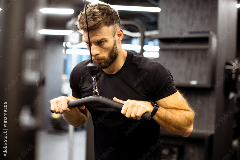Fototapeta premium Focused man performing strength training at the gym in the evening