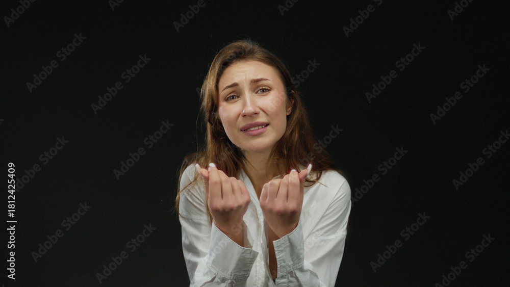 Fototapeta premium Woman expressing emotion with hands over isolated black background, wearing white shirt, conveying clear and impactful message with strong visual elements and intense focus.