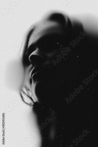 Beautiful young woman sensual portrait. Model illuminated with back light and visible silhouettes. Black and white image. Grunge, noise and motion blur effect applied. Retro vintage, gothic style