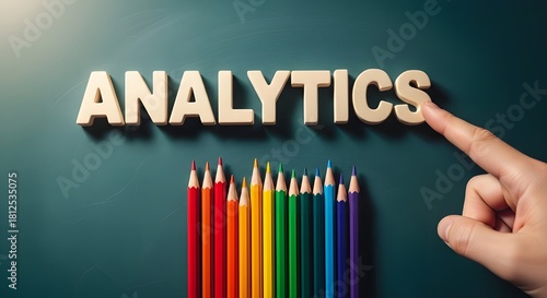 Hand adjusting the word analytics with colorful pencils below