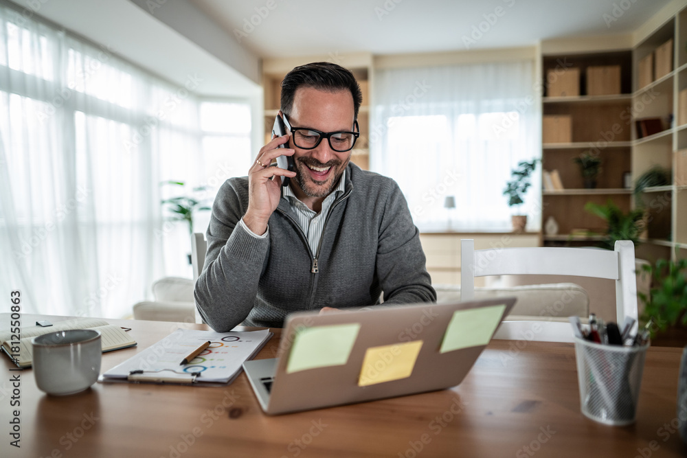 Obraz premium Happy man having phone call working from home office