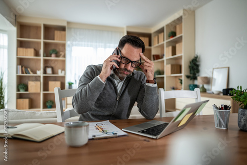 Foto Man working from home experiencing stress during phone call