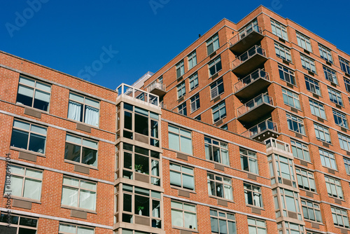 Modern brick apartment building with large windows and balconies in urban city under clear blue sky