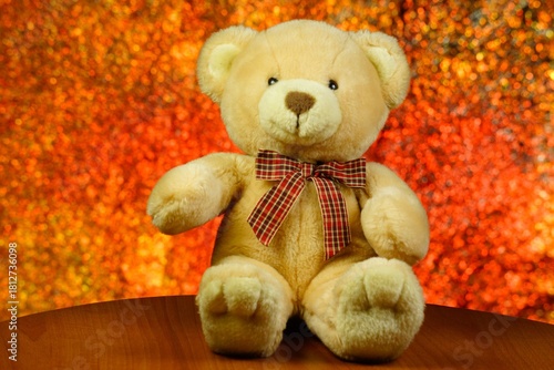 A toy teddy bear with a bow on a festive background of bokeh lights