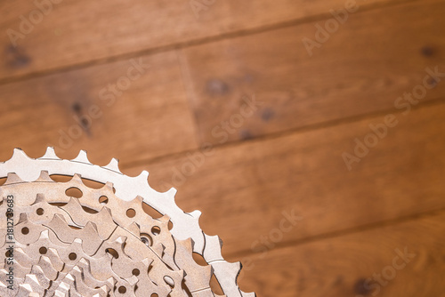 Close-up of a multi-sprocket bicycle cassette resting on wood flooring, showing gear progression and hub interface