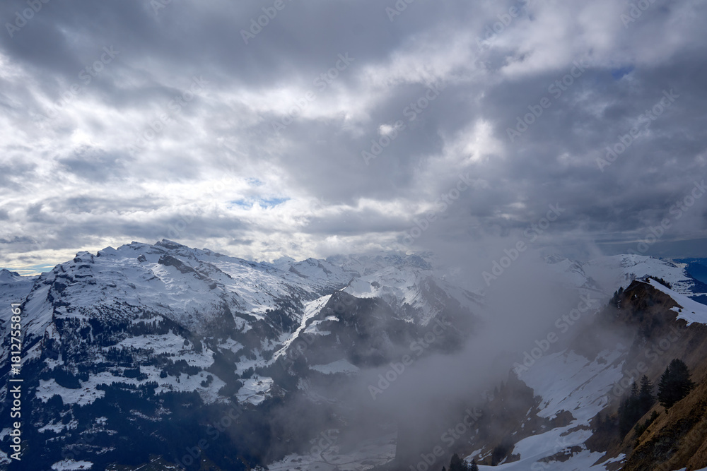 Naklejka premium Winter veil drapes snowed Swiss Alps as clouds drift over Hoch-Ybrig peaks.