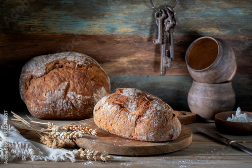 Fresh homemade bread and household utensils on a rustic table