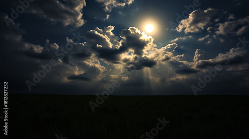 Wide grassland under moonlit sky filled with thick glowing clouds, rays of moonlight piercing through the clouds