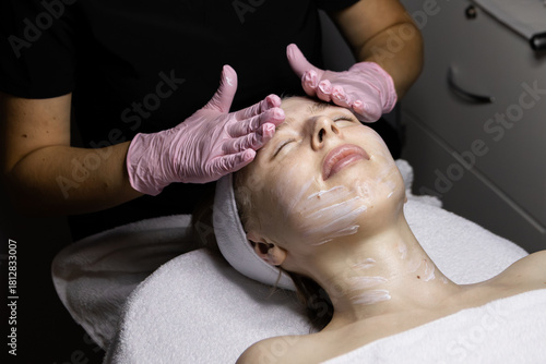 Face and neck massage at a beautician's appointment. Adult Caucasian woman gets treatments, specialist in pink latex gloves