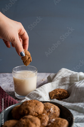 Hand dipping a homemade cookie into a glass of milk, close-up shot
