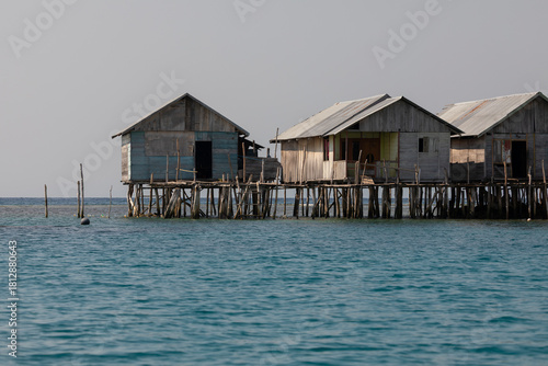 Humble houses supported by wooden poles, built over the water, in Pulau Taupan, an island in the Togian archipelago, Sulawesi, Indonesia