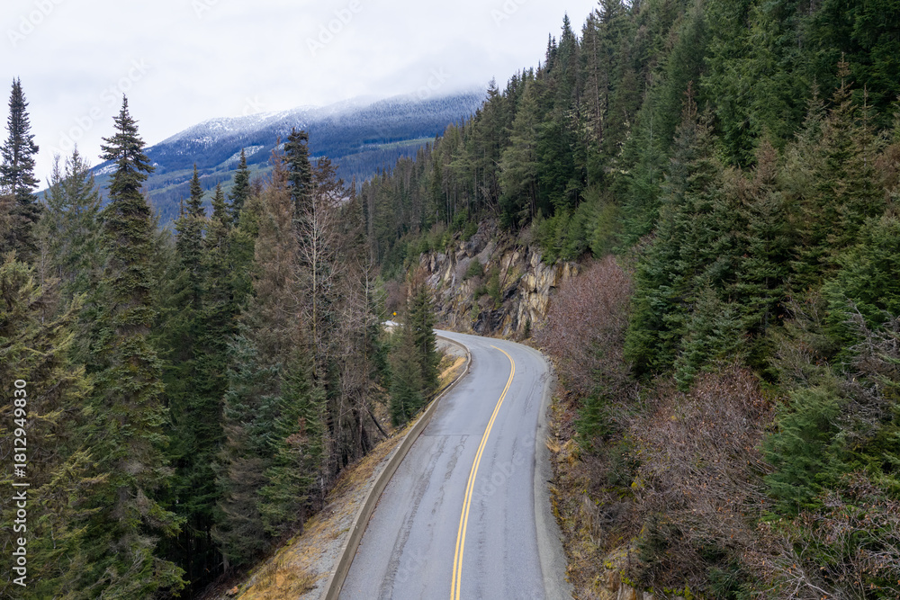 Obraz premium Winding Mountain Road Through Dense Forest in British Columbia, Canada on a Misty Day