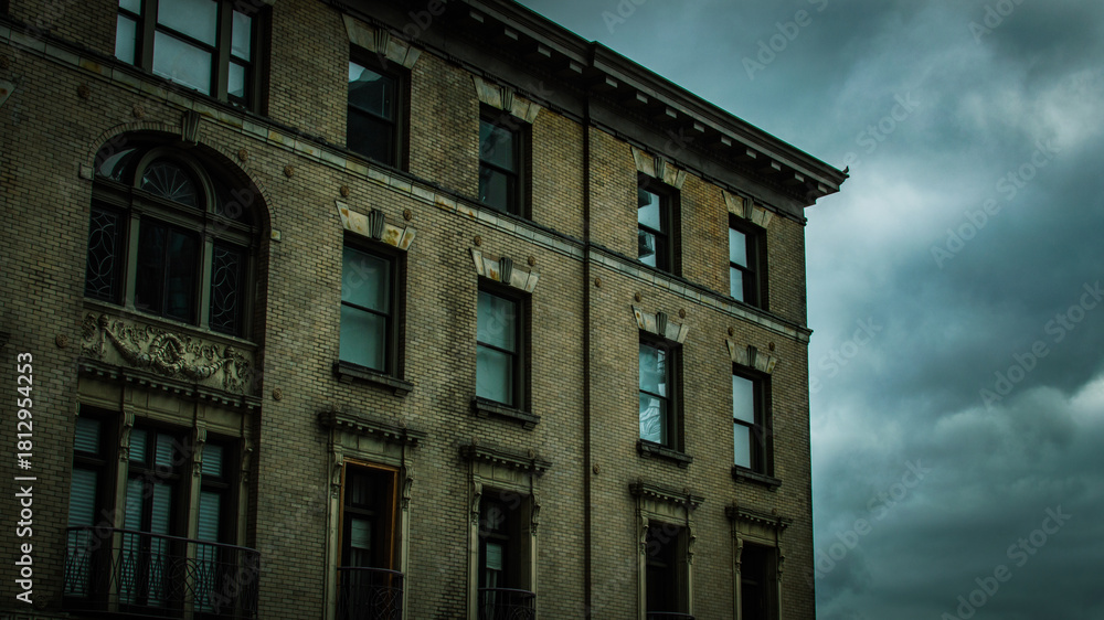 Obraz premium Historic Brick Building Facade Against Dramatic Cloudy Sky, Seattle