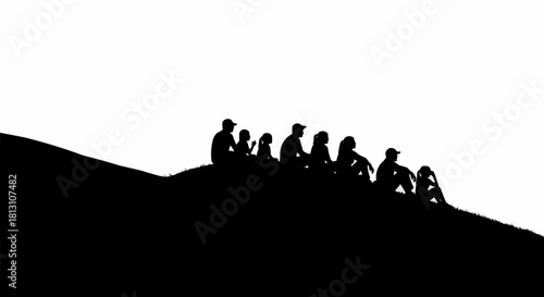 Silhouette of a group of people sitting together on a hilltop.