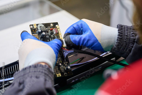Technician assembles electronic circuit board with precision in factory environment during daytime