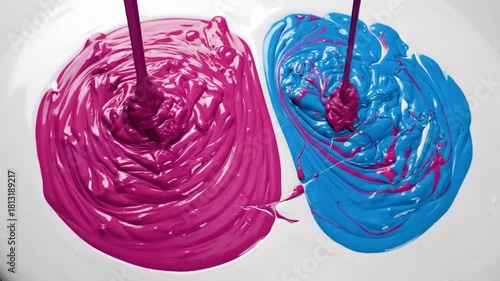 Vibrant magenta and electric blue liquids swirl and blend creating abstract patterns on a white