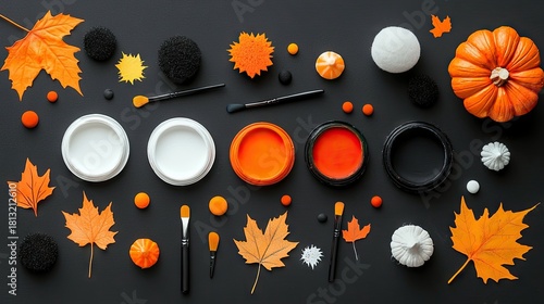 A flat lay arrangement of autumnal-themed makeup and face paint supplies, including orange and white paints, brushes, and decorative elements like fall leaves a