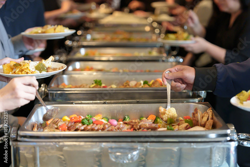 People's hands serving themselves at buffet during party or seminar in hotel, with a variety of food and drinks available.