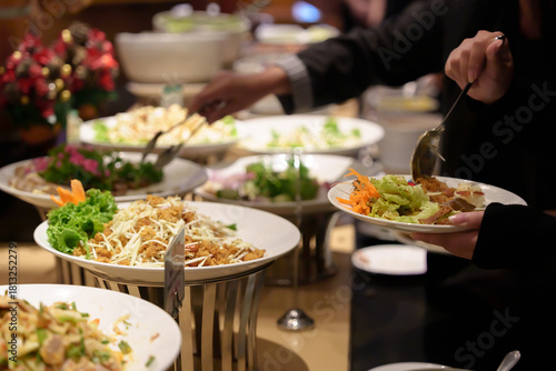 Fotografie People's hands serving themselves at buffet during party or seminar in hotel, with a variety of food and drinks available