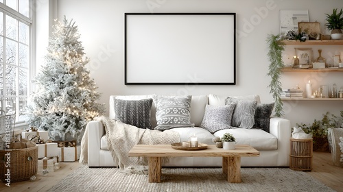 A bright and cozy living room is decorated for Christmas with a snowy tree and a large blank frame hanging above the comfortable sofa.