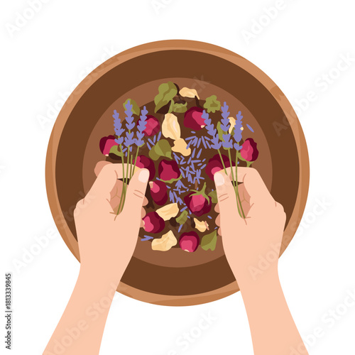 Overhead view of hands gently mixing a fragrant blend of dried rose buds, lavender, and herbs in a simple wooden bowl for aromatherapy.