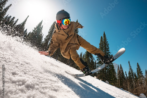 Snowboarder man jumps at big speed at forest ski slope