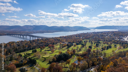 Hillside view of golf course and fall trees surrounding peaceful residential streets in Newburgh NY. Aerial highlights landscape design and seasonal foliage under bright clear skies.