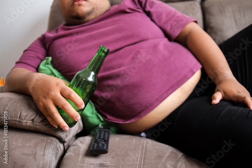 Unhealthy Lifestyle Choices with Fat Guy Lounging on the Couch with Beer Bottle