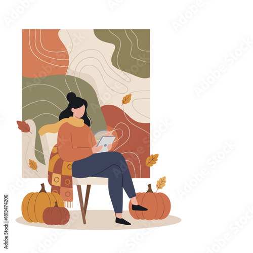 Woman uses a tablet in a cozy autumn setting surrounded by pumpkins and fall leaves