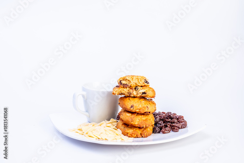 Delicious homemade almond and raisin cookies served with a cup of coffee on a white plate. Close-up of cookies with sliced almonds and raisins