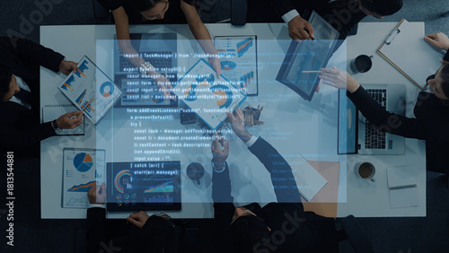 Photos A diverse business team collaborates in an office setting, analyzing data visualizations on digital devices, engaged in strategic discussions and planning