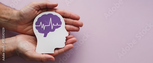 Hands gently cradling a paper cutout of a human head with a purple brain and heartbeat line inside symbolizing mental health awareness and care
