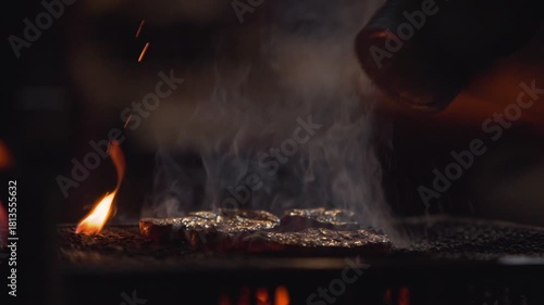 Slow motion showing flames and smoke rising from a hot grill at a night yatai stall in Fukuoka, Japan, with glowing orange tones and dramatic firelight reflections