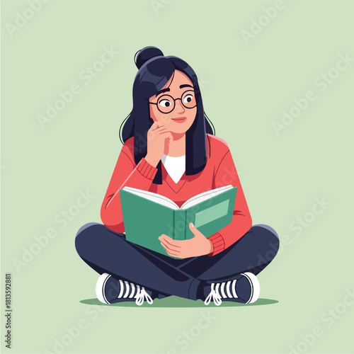 Young woman with glasses sitting crosslegged and reading a book.