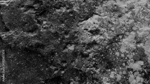 Dark rough rock texture with natural stone patterns and gritty surface details for backgrounds