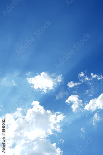 vertical image. Bright blue sky with soft white clouds, cloudscape background.