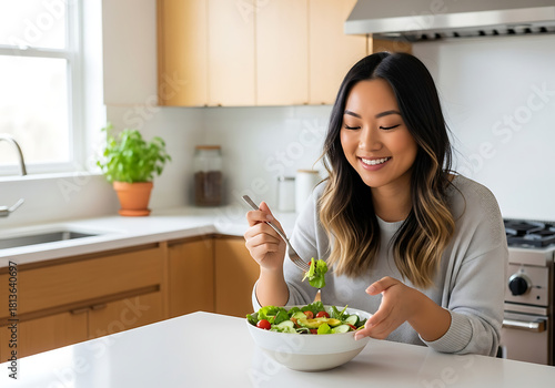 Happy woman enjoys fresh salad in bright modern kitchen, promoting healthy eating habits