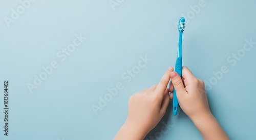 Child hands holding blue toothbrush on light blue background image