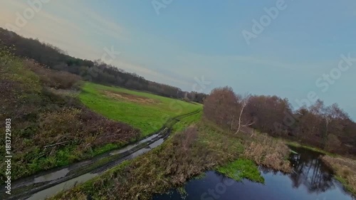 A low and fast drone flight over a river and meadow.