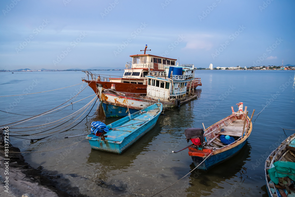 Fototapeta premium Traditional wooden fishing boats docked in a calm harbor with ropes and nets visible during a peaceful seaside day