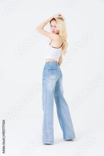 Asian confident beautiful attractive woman blonde long hair stand wear sleeveless top blue jeans on white background studio portrait fashion street outfit trendy style pose look at camera full length.